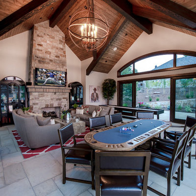 Example of a huge mountain style enclosed limestone floor and white floor game room design in Denver with a wall-mounted tv, beige walls, a standard fireplace and a stone fireplace