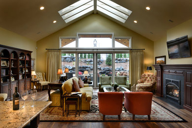 Imagen de sala de estar abierta de estilo americano con suelo de madera oscura, todas las chimeneas, marco de chimenea de madera y televisor colgado en la pared