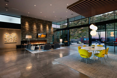 Example of a large trendy open concept limestone floor, brown floor, exposed beam and wall paneling family room design in Phoenix with brown walls, a hanging fireplace, a metal fireplace and a wall-mounted tv