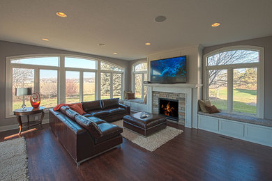 Design ideas for a medium sized classic enclosed games room in Minneapolis with beige walls, dark hardwood flooring, a standard fireplace, a stone fireplace surround, a wall mounted tv and brown floors.