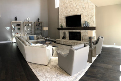 Inspiration for a large transitional dark wood floor family room remodel in Austin with gray walls, a stone fireplace and a wall-mounted tv