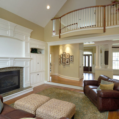 Inspiration for a mid-sized timeless enclosed medium tone wood floor family room remodel in Boston with no tv, yellow walls, a standard fireplace and a tile fireplace