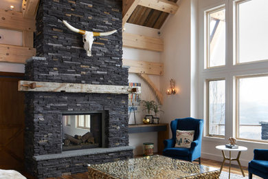 Ejemplo de sala de estar abierta clásica renovada grande con paredes blancas, suelo de madera en tonos medios, chimenea de doble cara, marco de chimenea de piedra y suelo marrón