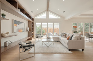 Modelo de sala de estar abierta tradicional renovada grande con paredes beige, suelo de madera clara, televisor colgado en la pared y suelo marrón