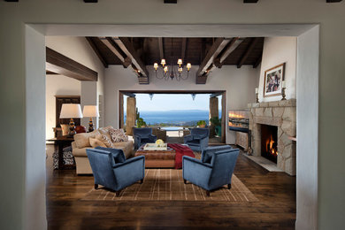 This is an example of a mediterranean games room in Santa Barbara with white walls, dark hardwood flooring, a standard fireplace and a stone fireplace surround.
