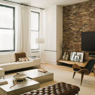 Imagen de sala de estar abierta, urbana, grande, sin chimenea, con paredes blancas, suelo de madera clara, televisor colgado en la pared y suelo beige
