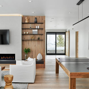 Example of a large trendy open concept light wood floor and beige floor game room design in Denver with white walls, a ribbon fireplace, a wall-mounted tv and a plaster fireplace
