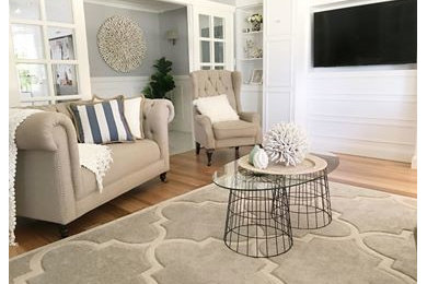 Diseño de sala de estar abierta costera de tamaño medio con paredes grises, suelo de madera clara, pared multimedia y suelo marrón