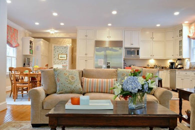 Ejemplo de sala de estar abierta clásica renovada de tamaño medio sin chimenea con paredes beige, suelo de madera clara y televisor colgado en la pared