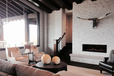 Imagen de sala de estar abierta moderna extra grande con paredes beige, suelo de madera oscura, todas las chimeneas, marco de chimenea de piedra y suelo marrón