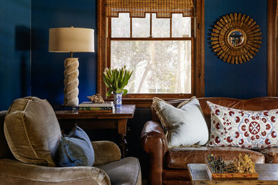 На фото: изолированная гостиная комната среднего размера в стиле неоклассика (современная классика) с с книжными шкафами и полками, синими стенами, паркетным полом среднего тона и телевизором на стене без камина