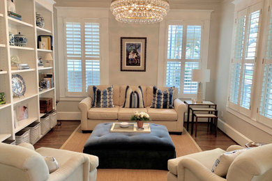 Ejemplo de sala de estar con biblioteca cerrada de estilo americano de tamaño medio sin televisor con paredes blancas, suelo de madera en tonos medios y suelo marrón
