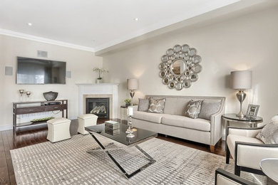 Imagen de sala de estar actual con paredes grises, suelo de madera en tonos medios, televisor colgado en la pared y chimenea de esquina