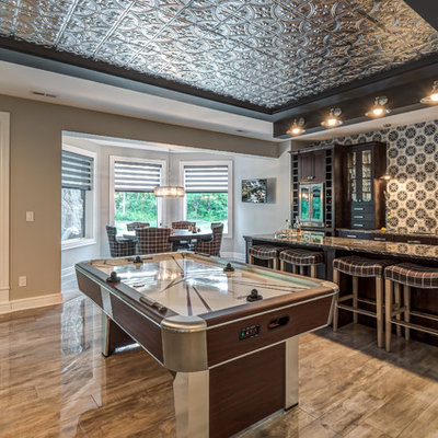 Example of a huge transitional open concept porcelain tile and brown floor family room design in Cincinnati with a bar, gray walls, no fireplace and a wall-mounted tv
