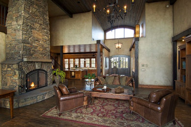 Inspiration for a large rustic open plan games room in Other with beige walls, dark hardwood flooring, a standard fireplace, a stone fireplace surround and brown floors.