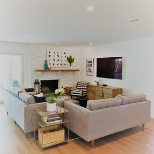 Inspiration for a mid-sized contemporary open concept light wood floor and beige floor family room remodel in Austin with white walls, a standard fireplace, a stone fireplace and a wall-mounted tv