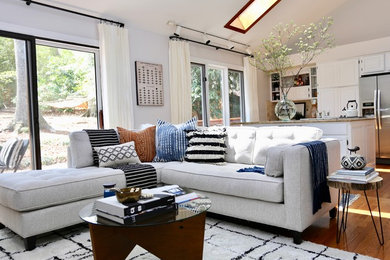 Immagine di un soggiorno bohémian aperto con pareti bianche e pavimento in legno massello medio