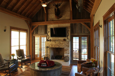 Klassisches Wohnzimmer mit beiger Wandfarbe, braunem Holzboden, Kamin, Kaminumrandung aus Stein und TV-Wand in Austin
