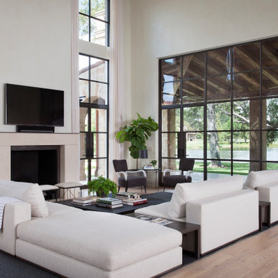 Tuscan open concept light wood floor family room photo in Houston with a standard fireplace, a wall-mounted tv and white walls