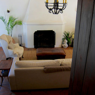 Mittelgroßes, Abgetrenntes Mediterranes Wohnzimmer mit weißer Wandfarbe, Terrakottaboden, Kamin, Kaminumrandung aus Beton und rotem Boden in Santa Barbara