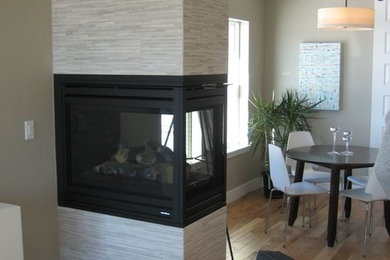Ejemplo de sala de estar abierta moderna pequeña con paredes beige, suelo de madera en tonos medios, chimenea de doble cara y marco de chimenea de baldosas y/o azulejos