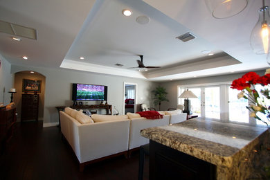 Ejemplo de sala de estar abierta asiática de tamaño medio con paredes grises, suelo de madera oscura, televisor colgado en la pared y suelo marrón