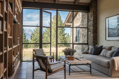 Inspiration pour une salle de séjour chalet avec une bibliothèque ou un coin lecture, un mur beige, un sol en bois brun, aucune cheminée et aucun téléviseur.