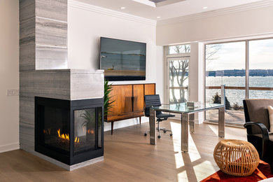 Large contemporary open plan games room in Providence with white walls, light hardwood flooring, a two-sided fireplace, a stone fireplace surround, a wall mounted tv and brown floors.