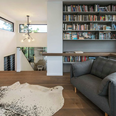 Trendy loft-style medium tone wood floor and brown floor family room library photo in Brisbane with white walls
