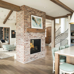 Foto de sala de estar con rincón musical abierta, clásica renovada, con paredes beige, suelo de madera en tonos medios, chimenea de doble cara, marco de chimenea de ladrillo y suelo marrón