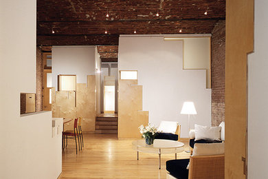 Foto de sala de estar tipo loft actual grande con suelo de madera clara y televisor retractable