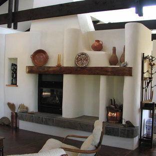 Imagen de sala de estar abierta, de estilo americano, de tamaño medio, sin televisor, con paredes blancas, suelo de madera oscura, chimenea tradicional y marco de chimenea de hormigón