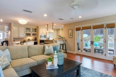 Example of a mid-sized beach style open concept medium tone wood floor and brown floor family room design in Orange County with beige walls, a media wall and no fireplace