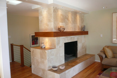 Diseño de sala de estar abierta clásica renovada con paredes verdes, suelo de madera clara, todas las chimeneas y marco de chimenea de piedra