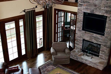 Imagen de sala de estar abierta tradicional renovada grande con paredes amarillas, suelo de madera oscura, todas las chimeneas, marco de chimenea de piedra y pared multimedia