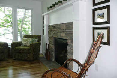 他の地域にある高級な中くらいなカントリー風のおしゃれなオープンリビング (白い壁、淡色無垢フローリング、標準型暖炉、石材の暖炉まわり、マルチカラーの床) の写真