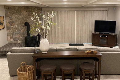 Example of a mid-sized transitional enclosed carpeted, gray floor and coffered ceiling family room design in Manchester with gray walls, a wood stove, a stone fireplace and a corner tv
