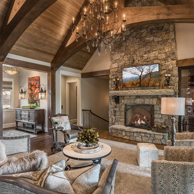Family room - huge rustic open concept dark wood floor family room idea in Other with a standard fireplace, a stone fireplace, gray walls and a wall-mounted tv