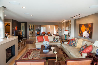 Imagen de sala de estar abierta contemporánea de tamaño medio con paredes marrones, suelo de madera en tonos medios, todas las chimeneas, marco de chimenea de yeso y televisor independiente