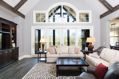 Diseño de sala de estar abierta tradicional renovada grande con paredes grises, suelo de madera oscura, chimenea de esquina, marco de chimenea de piedra, pared multimedia y alfombra