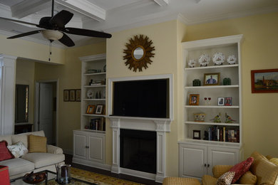 Foto de sala de estar abierta tradicional de tamaño medio con paredes amarillas, todas las chimeneas, marco de chimenea de yeso, pared multimedia, suelo vinílico y suelo marrón