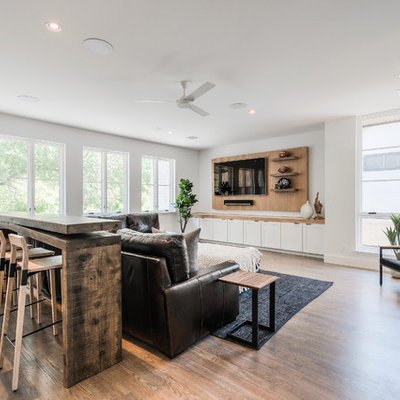 Example of a large trendy open concept light wood floor game room design in Dallas with white walls, no fireplace and a media wall