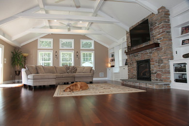 Family room - large transitional open concept dark wood floor family room idea in Philadelphia with beige walls, a standard fireplace, a stone fireplace and a wall-mounted tv
