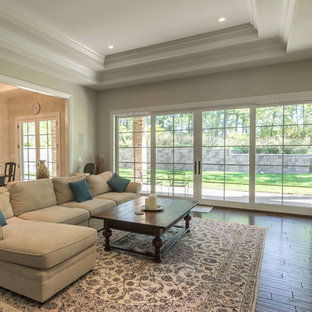 Example of a large transitional open concept medium tone wood floor and brown floor family room library design in Chicago with white walls, a standard fireplace, a wood fireplace surround and a wall-mounted tv