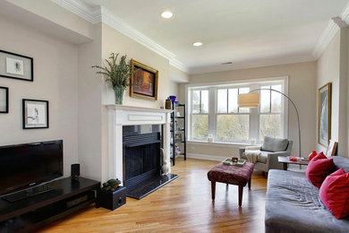 Large eclectic enclosed medium tone wood floor family room photo in Chicago with beige walls, a standard fireplace, a stone fireplace and a concealed tv