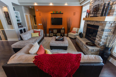 Family room - large dark wood floor family room idea in Edmonton with orange walls, a standard fireplace, a stone fireplace and a wall-mounted tv