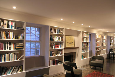 Diseño de sala de estar con biblioteca abierta minimalista con paredes blancas, suelo de madera oscura, todas las chimeneas y marco de chimenea de ladrillo