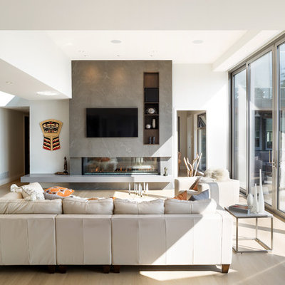 Example of a large trendy open concept light wood floor family room design in Vancouver with white walls, a two-sided fireplace, a stone fireplace and a wall-mounted tv