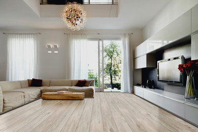 Diseño de sala de estar abierta contemporánea grande con paredes blancas, suelo de madera clara, televisor colgado en la pared y suelo beige