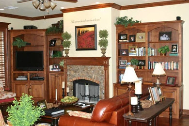 Inspiration for a timeless medium tone wood floor family room remodel in Oklahoma City with beige walls, a standard fireplace, a stone fireplace and a media wall